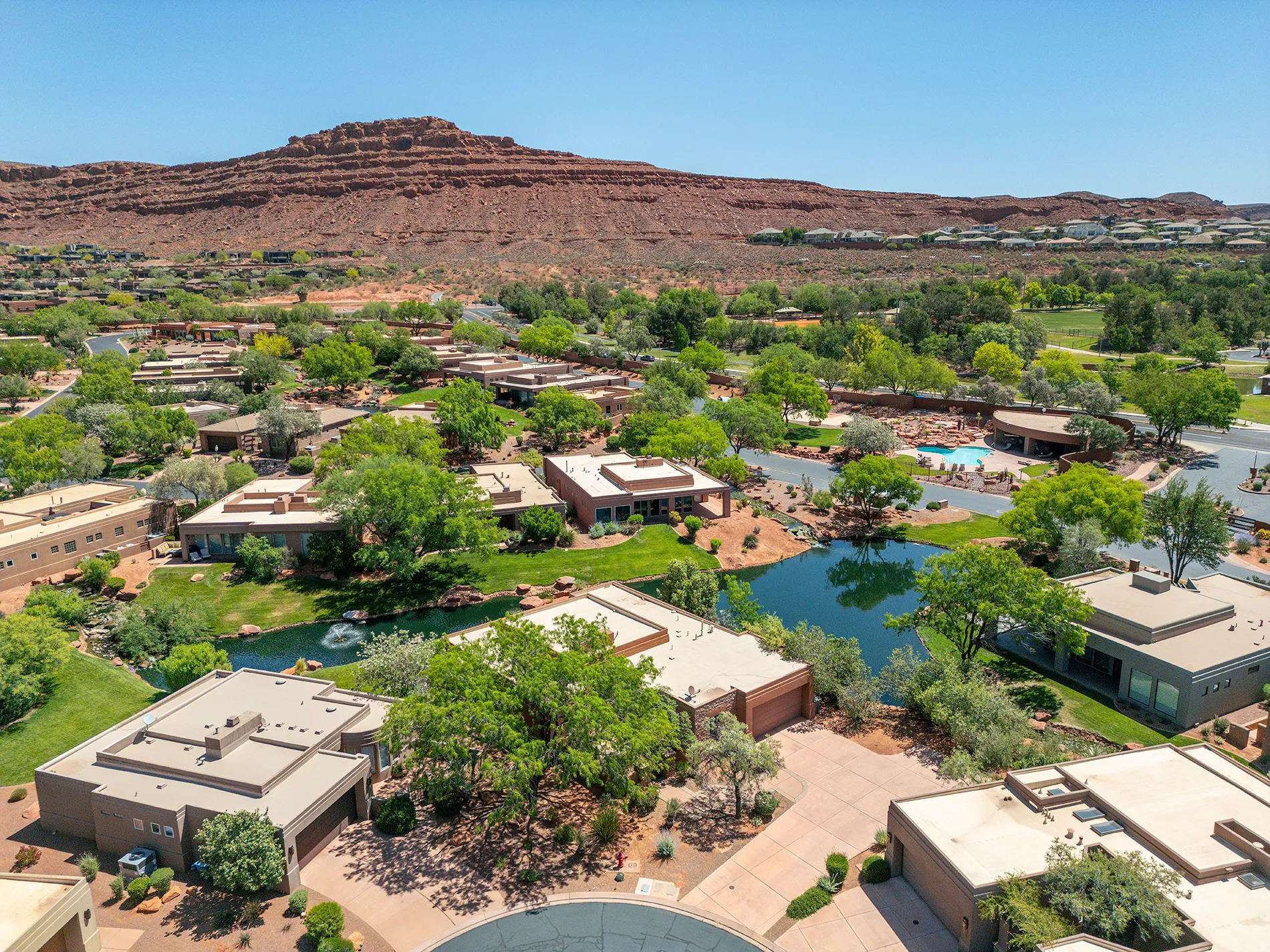 Community featuring a large pond, mature landscaping, and a swimming pool