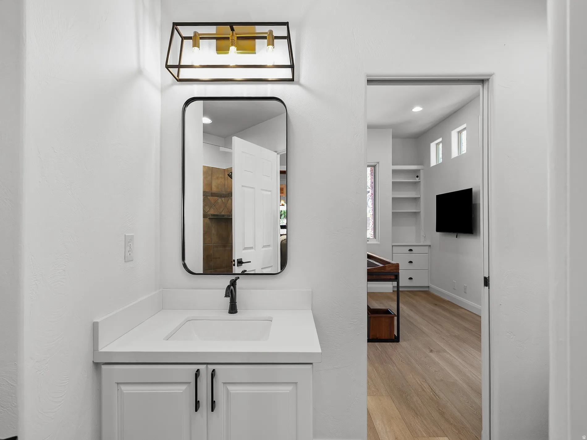 White vanity with shaker-style cabinetry, matte black hardware, and integrated sink