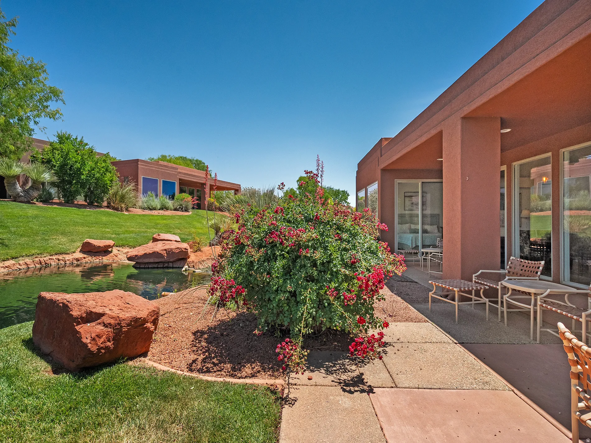 Expansive patio with direct access to a water feature, surrounded by mature landscaping and a manicured lawn