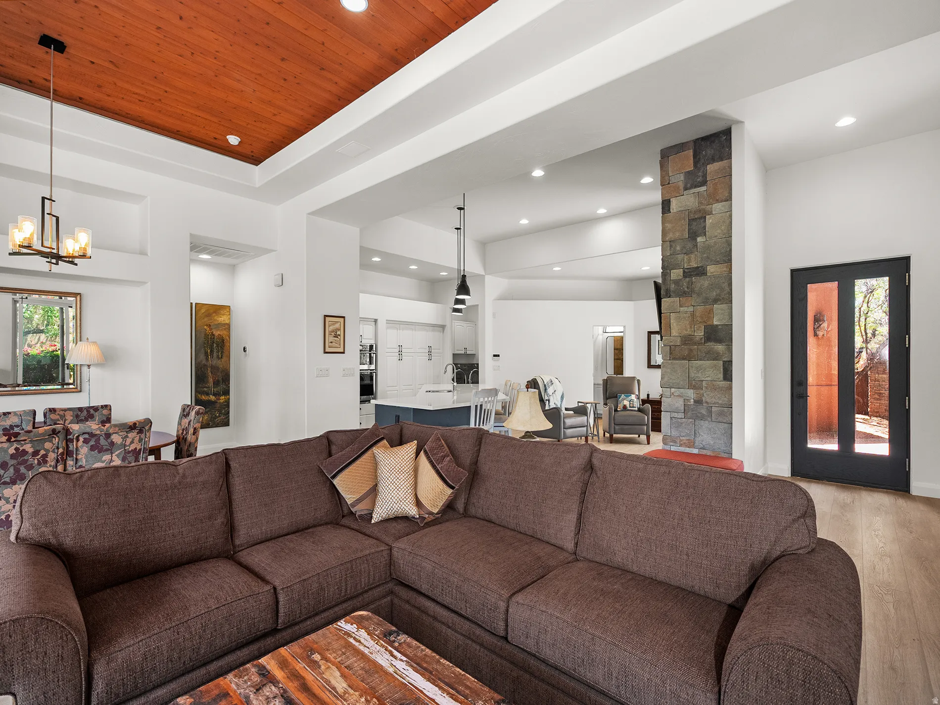 Vaulted wood-paneled ceiling, recessed lighting, stone-clad architectural feature, wood-finish flooring, and a glass-paneled entry door
