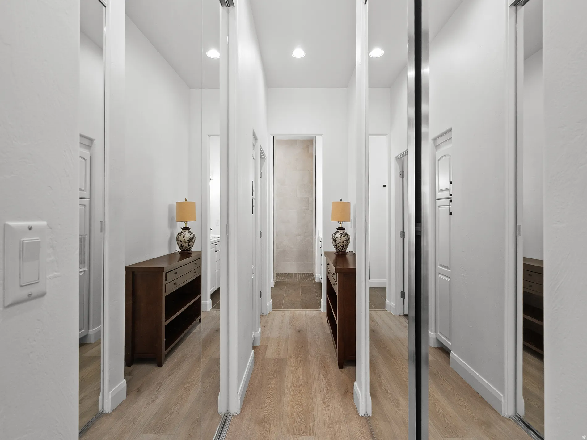 Hallway featuring wood-finish flooring, recessed lighting, and mirrored closet doors