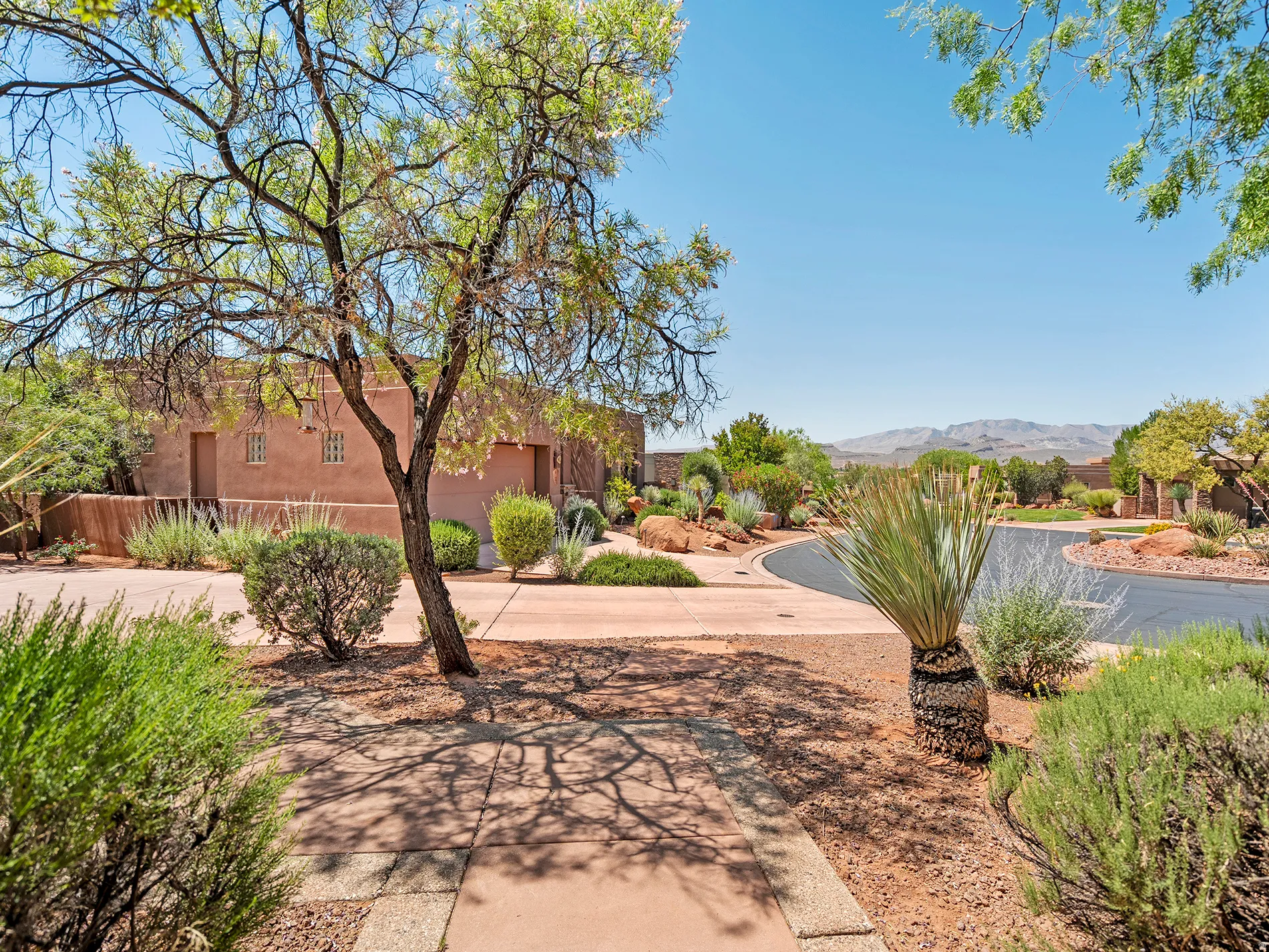 Southwestern architectural style with a stucco exterior, integrated garage, and a concrete paver driveway