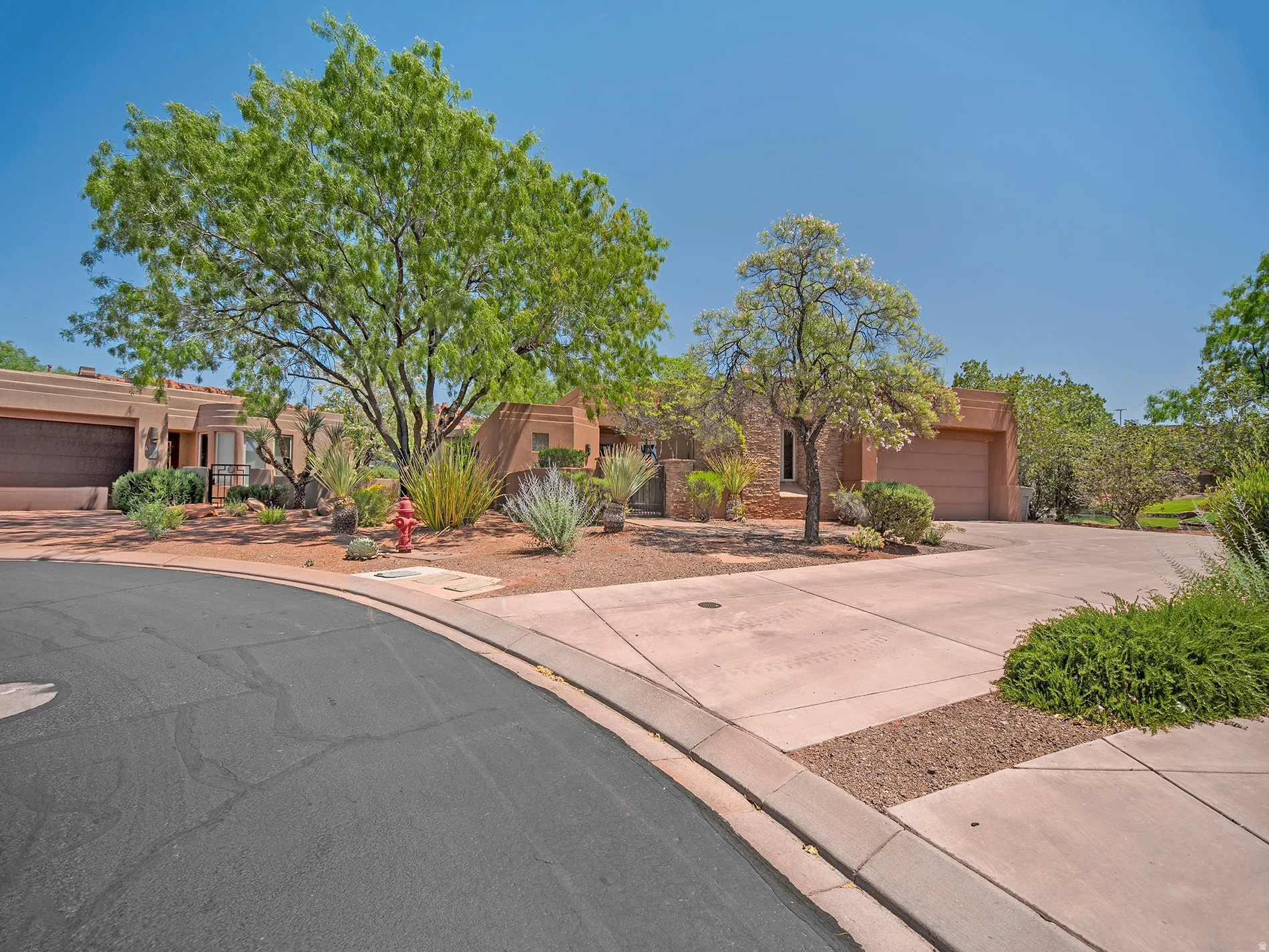 Southwestern-style exterior with a stucco finish, integrated garage, and mature desert landscaping