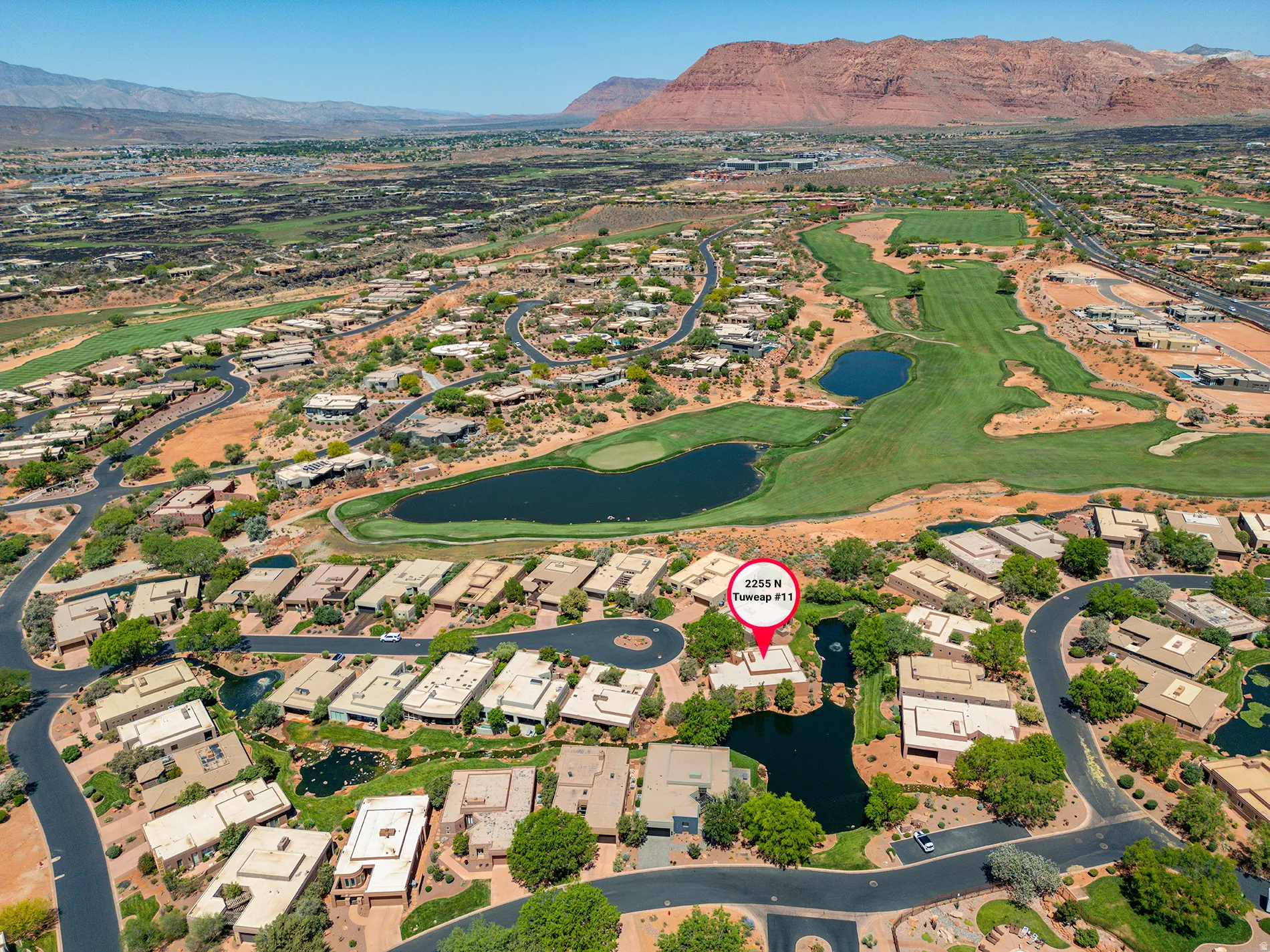 Community featuring extensive golf course grounds, multiple water features, residential properties, and paved roadways