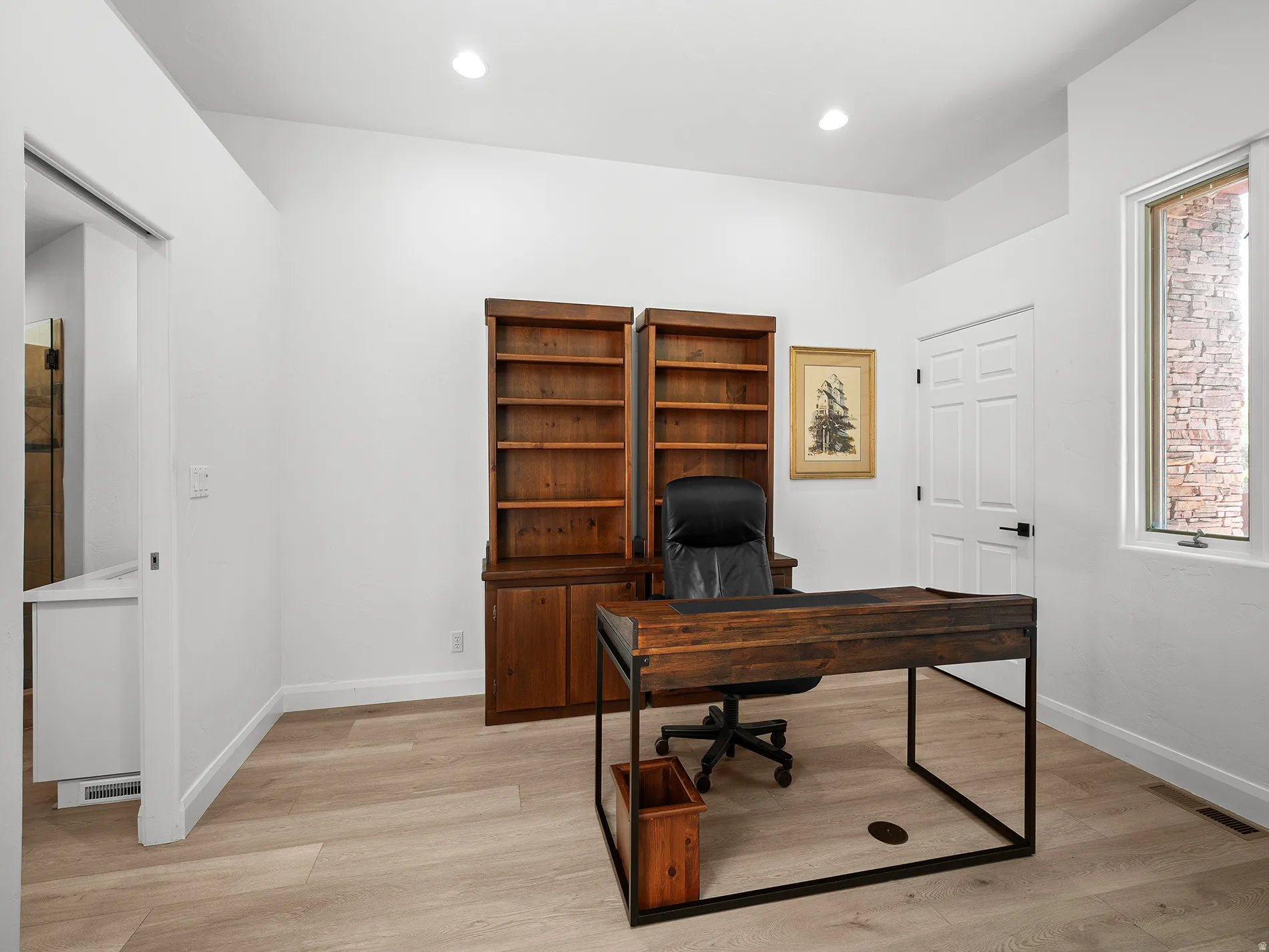 Recessed lighting, wood-finish flooring, built-in shelving, white paneled door, and a single-pane window