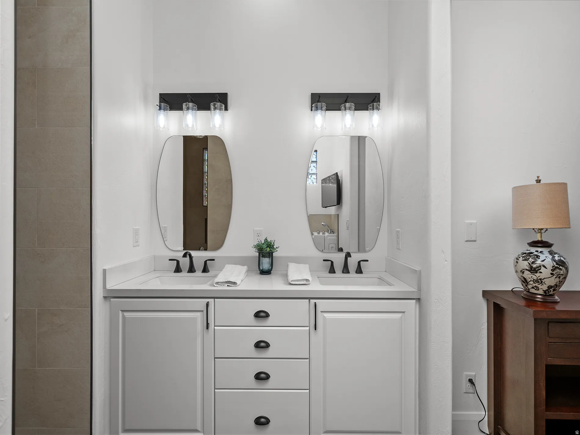 Dual vanity featuring undermount sinks, stone countertops, and matte black fixtures