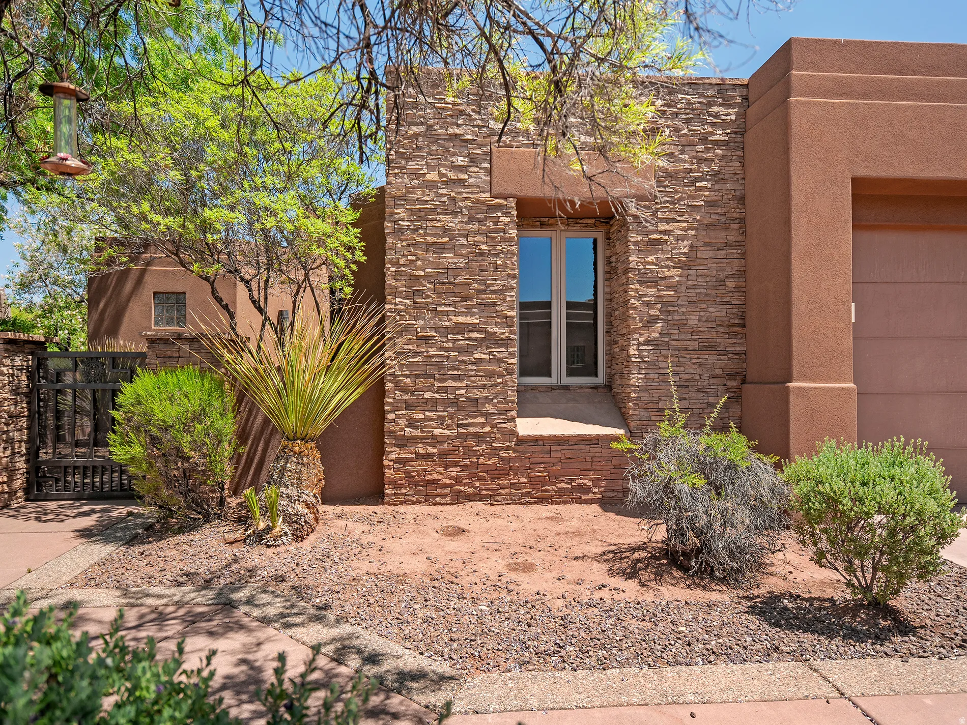 Stucco exterior with stone veneer accents, double-pane window, and desert-adapted landscaping