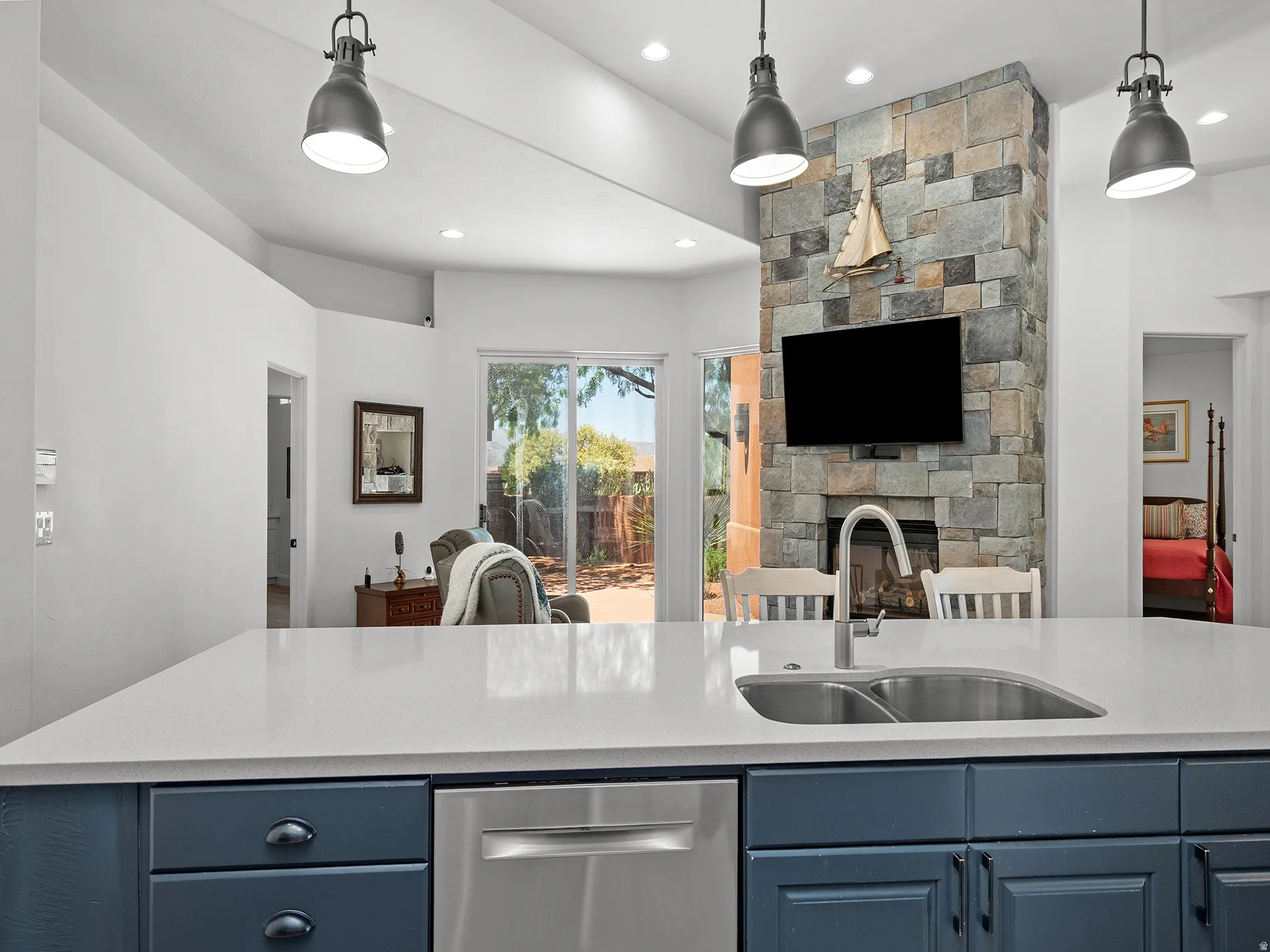 Kitchen island with white countertop, undermount stainless steel sink, and blue cabinetry