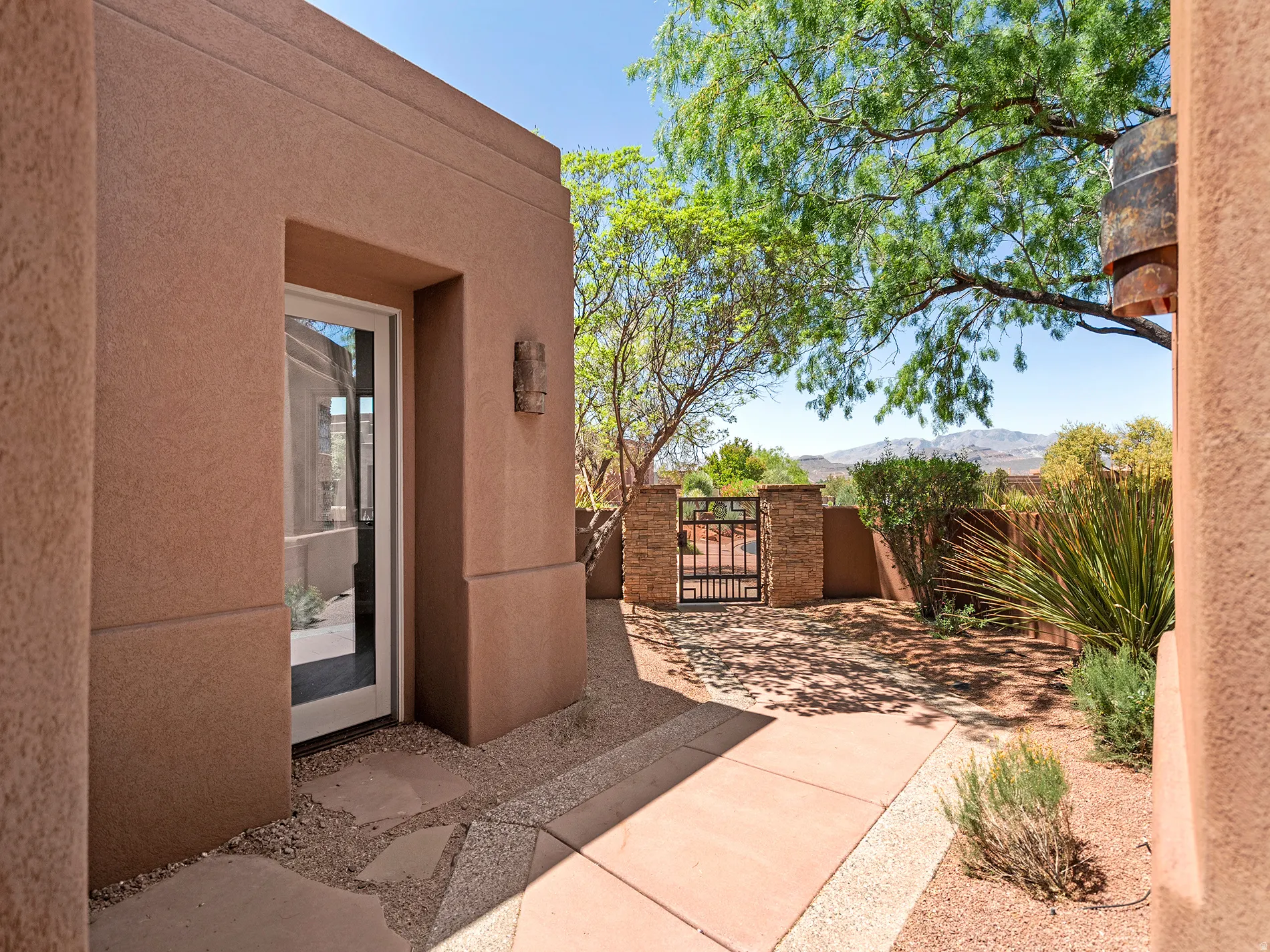 Stucco exterior with a glass-paneled door, decorative exterior lighting, and a paved walkway