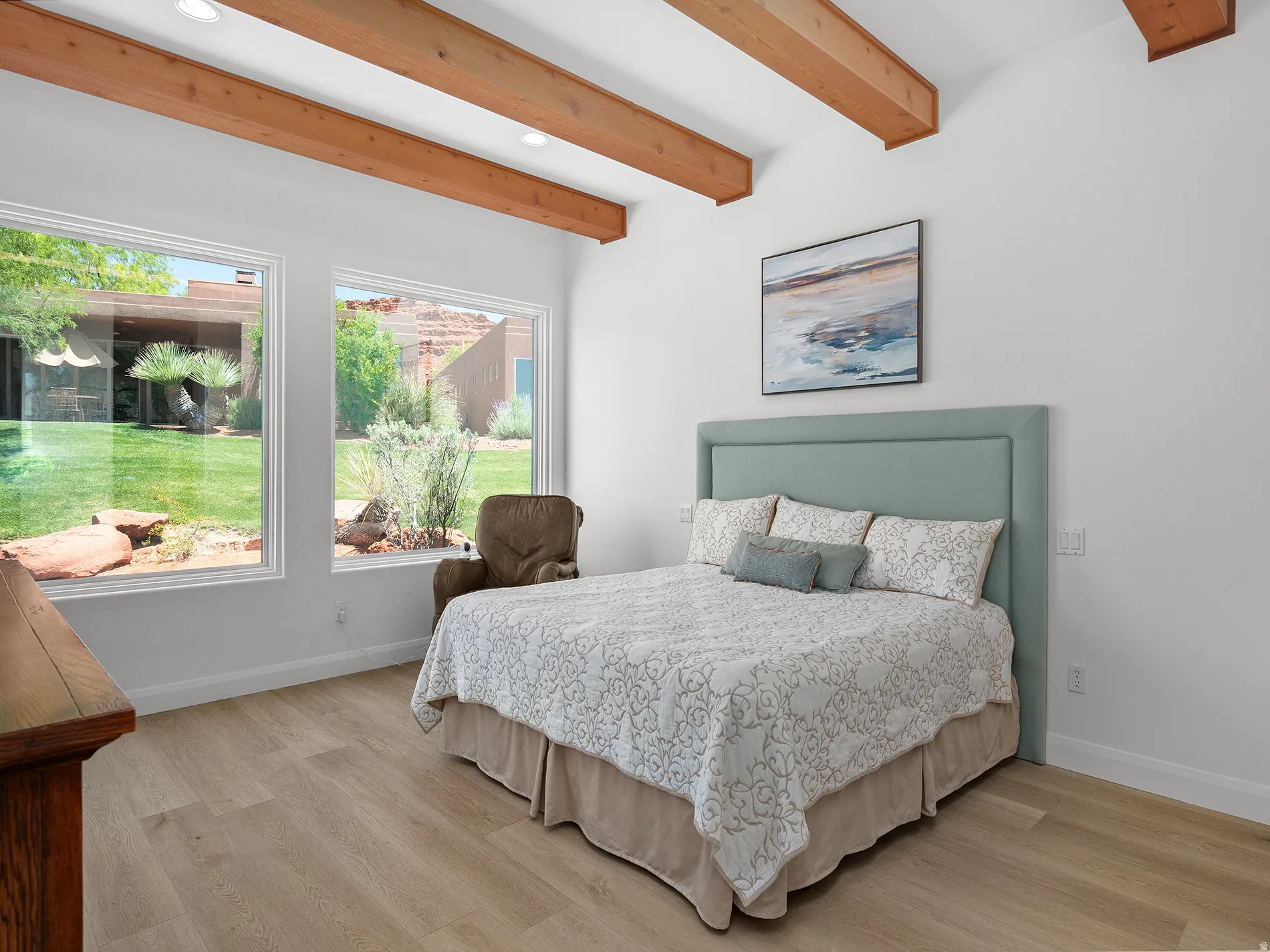 Vaulted ceiling with exposed wood beams, recessed lighting, and large windows with exterior views