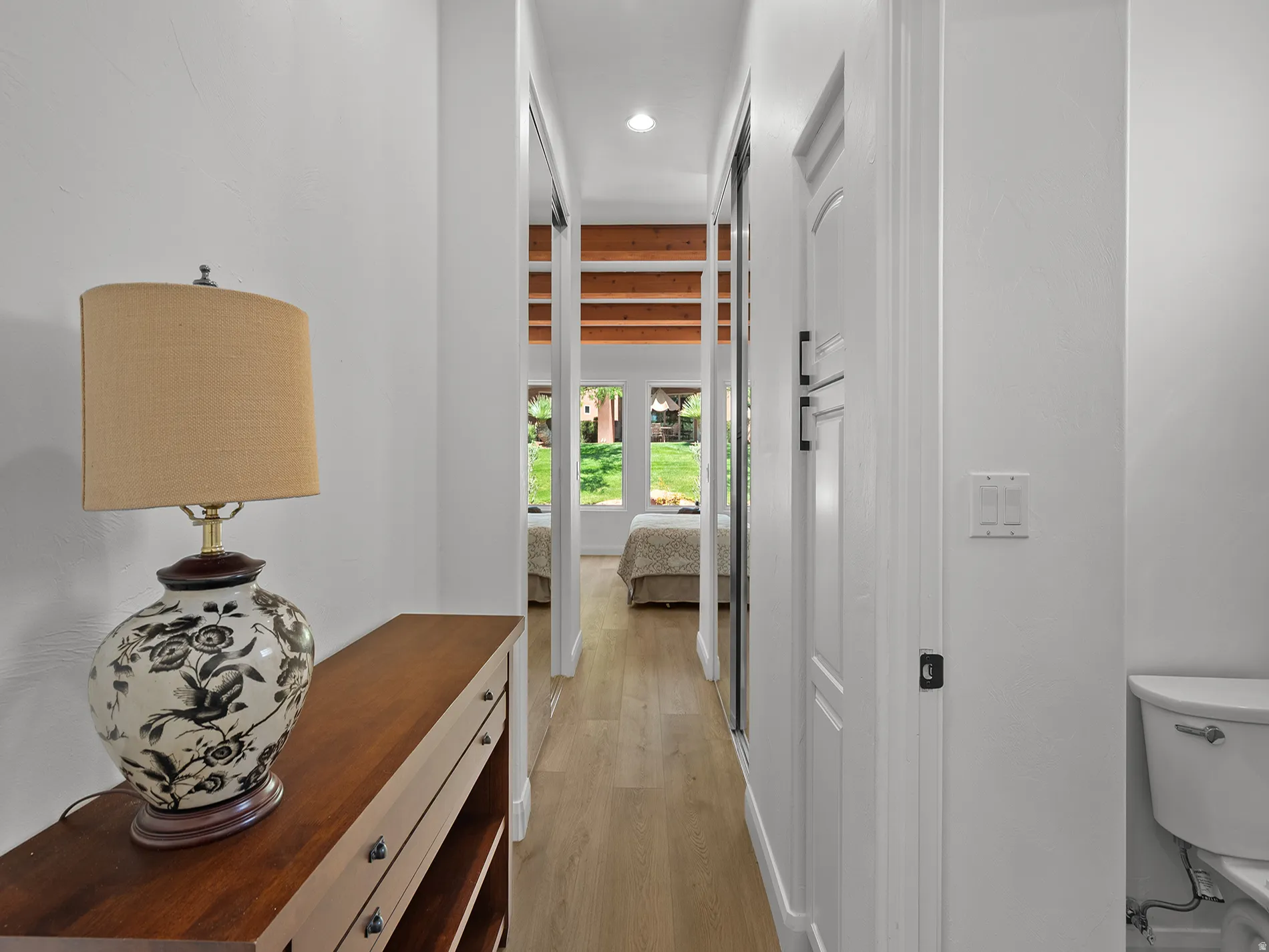 Hallway featuring wood-finish flooring, white walls, and built-in doors