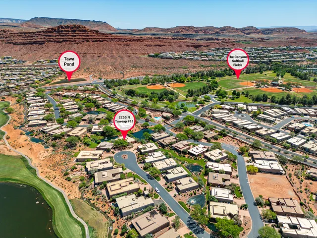 Aerial overview featuring a residential community, surrounding red rock formations, and green recreational areas
