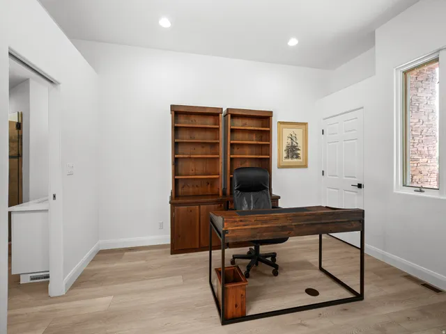 Recessed lighting, wood-finish flooring, built-in shelving, white paneled door, and a single-pane window