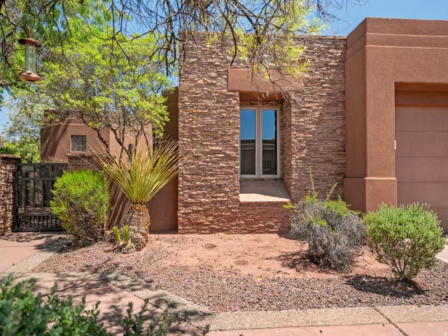 Stucco exterior with stone veneer accents, double-pane window, and desert-adapted landscaping