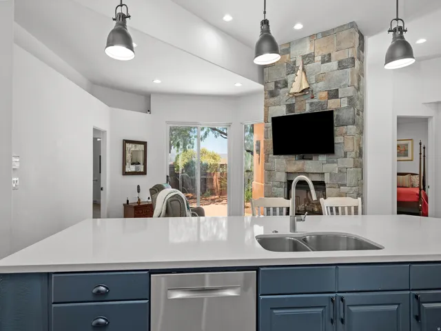 Kitchen island with white countertop, undermount stainless steel sink, and blue cabinetry