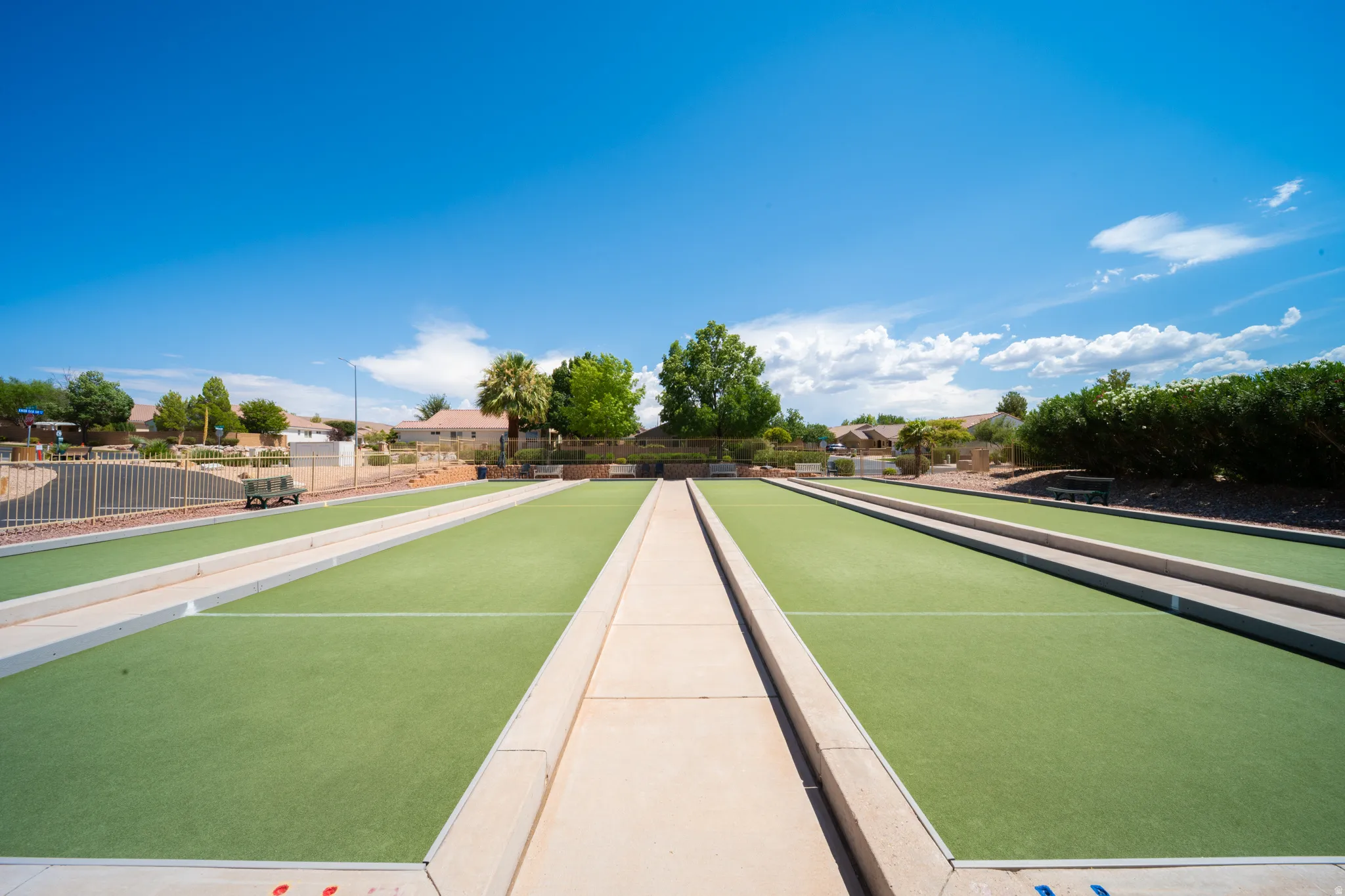 Multiple bocce ball courts with synthetic turf surfaces, bordered by concrete pathways