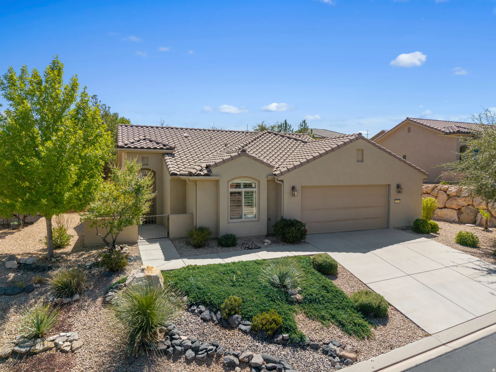 Stucco exterior with a tiled roof, an attached garage, and a concrete driveway