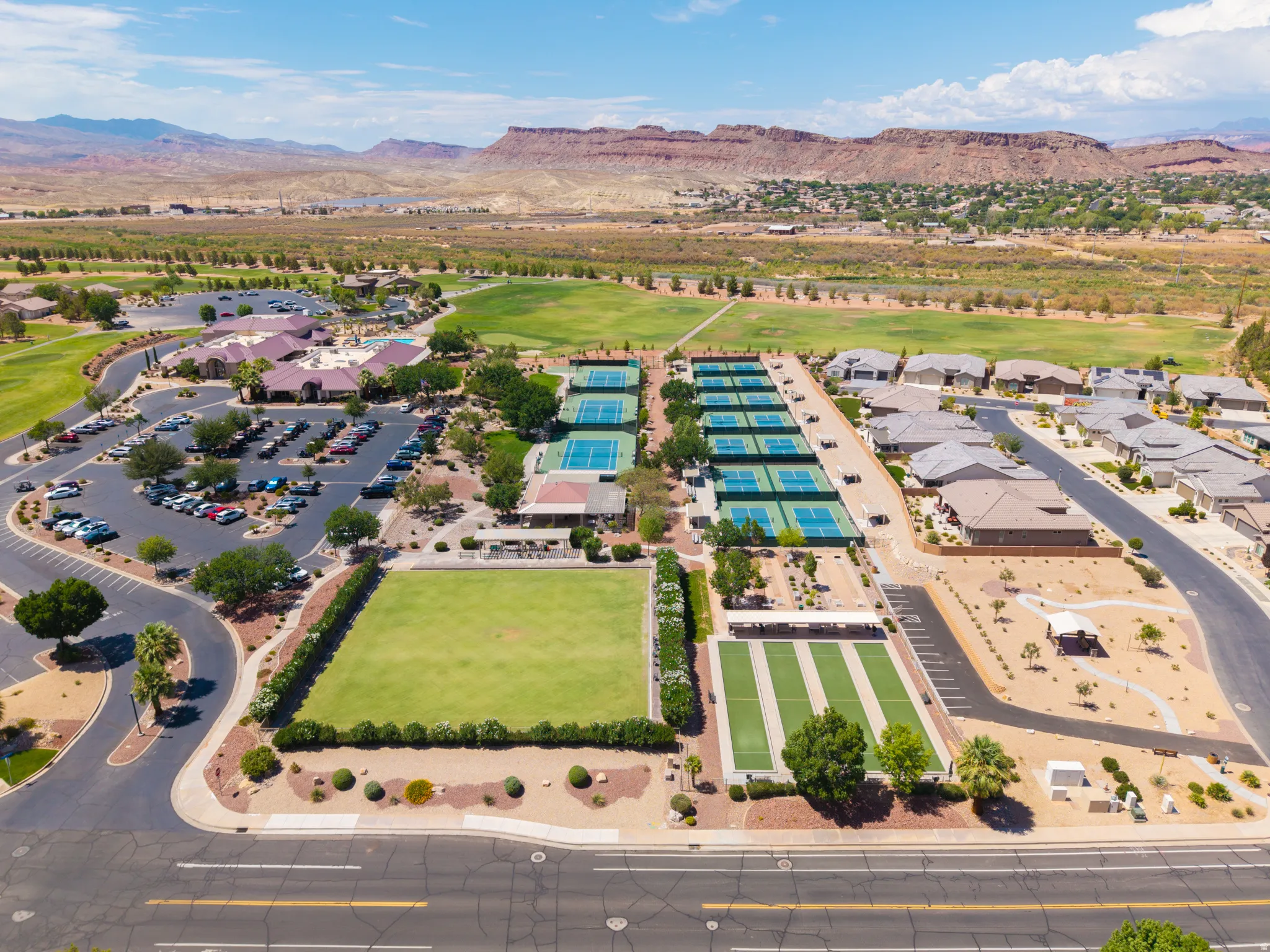 Expansive community featuring multiple tennis courts, a large green space, and a clubhouse with ample parking
