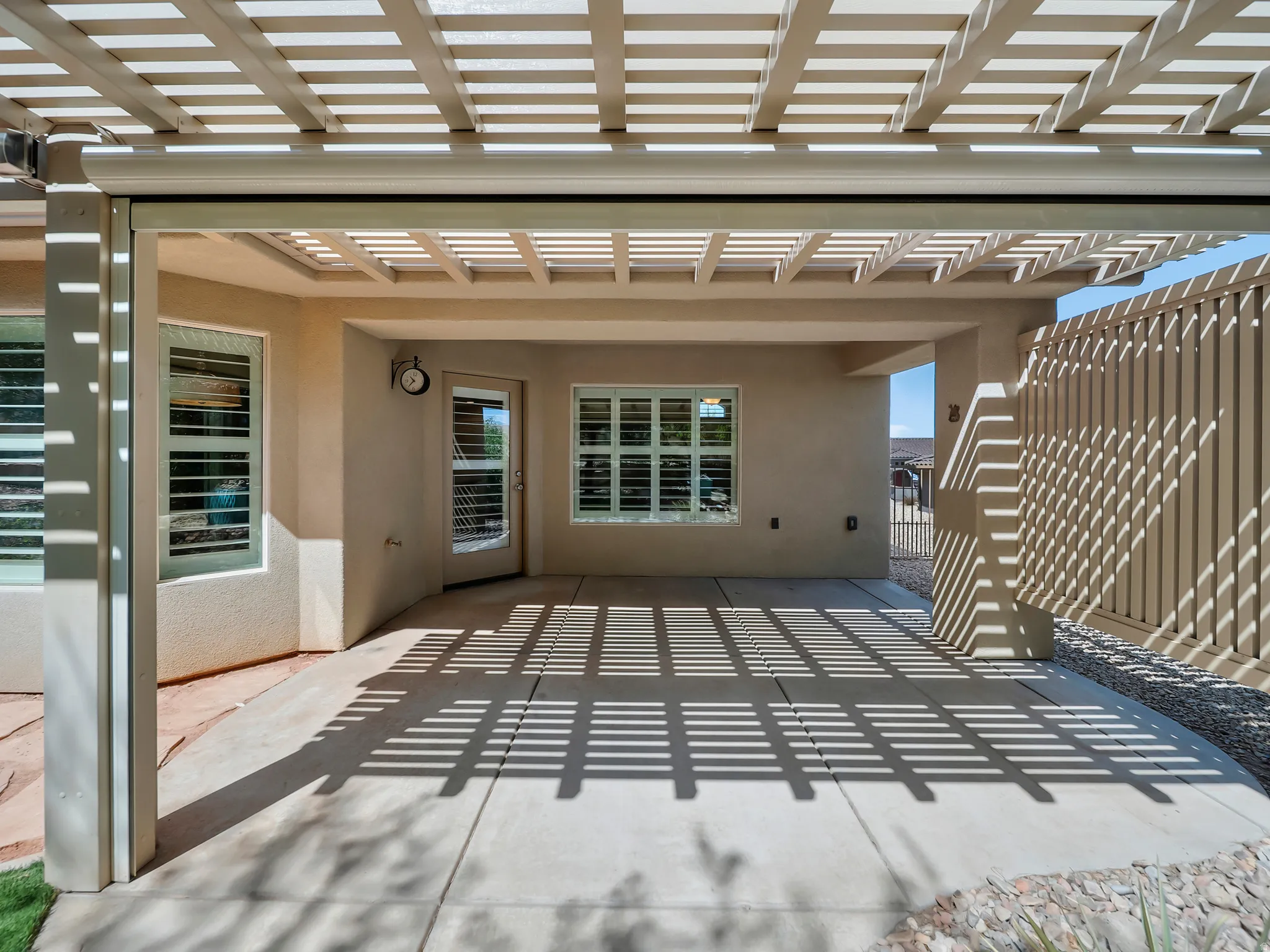 Covered patio featuring a slatted pergola roof and concrete flooring