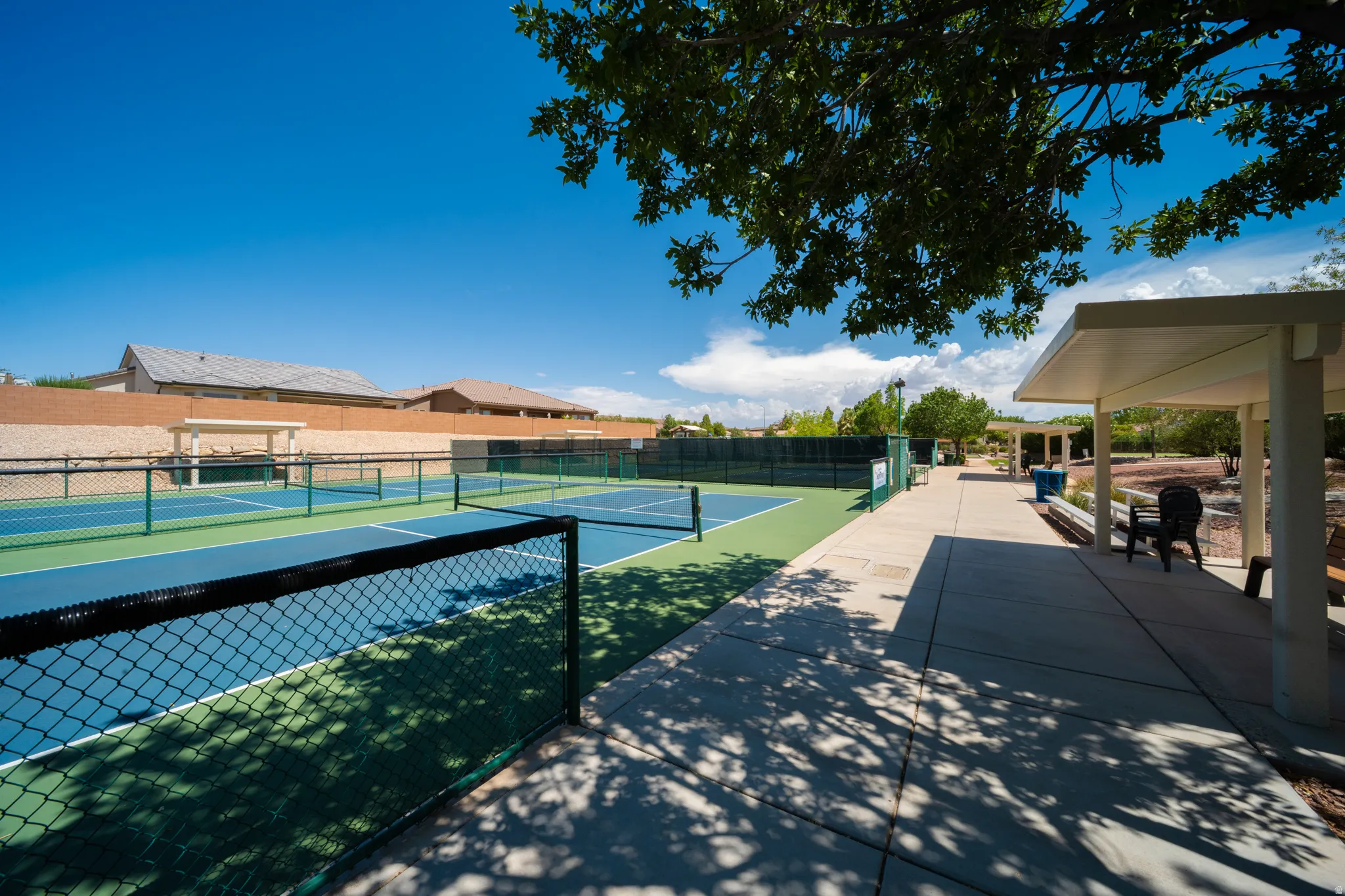 Multiple outdoor courts with mesh fencing, concrete walkways, and covered seating areas