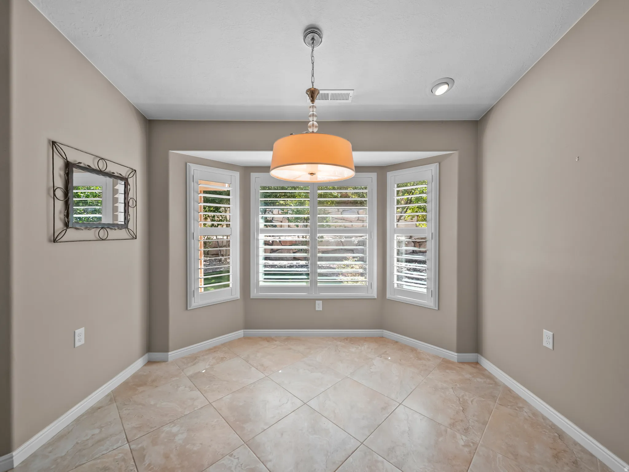 Bay window with plantation shutters, tile flooring, recessed lighting, and a decorative pendant light fixture