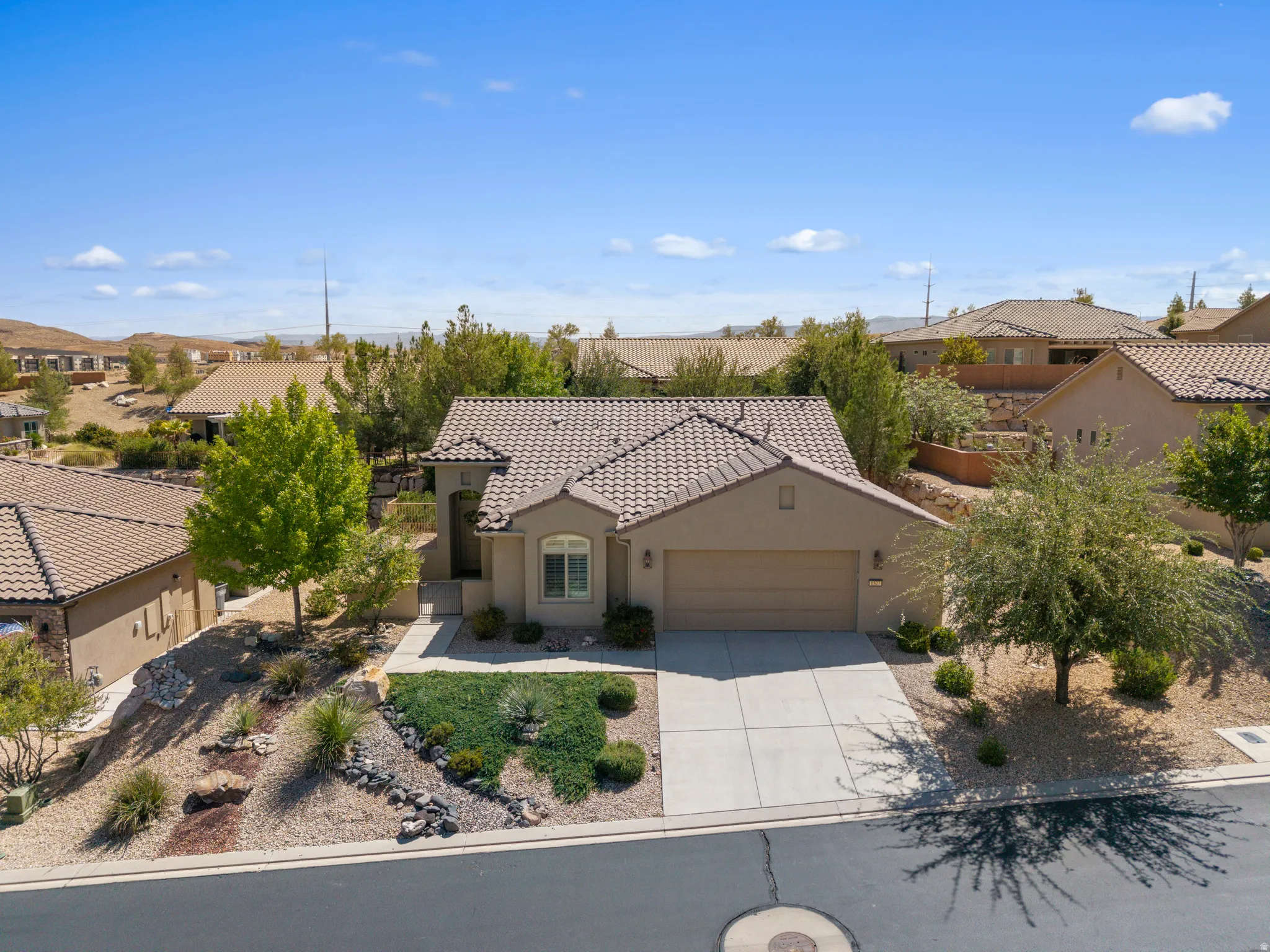 Mediterranean-style exterior with a tile roof, attached two-car garage, and a concrete driveway
