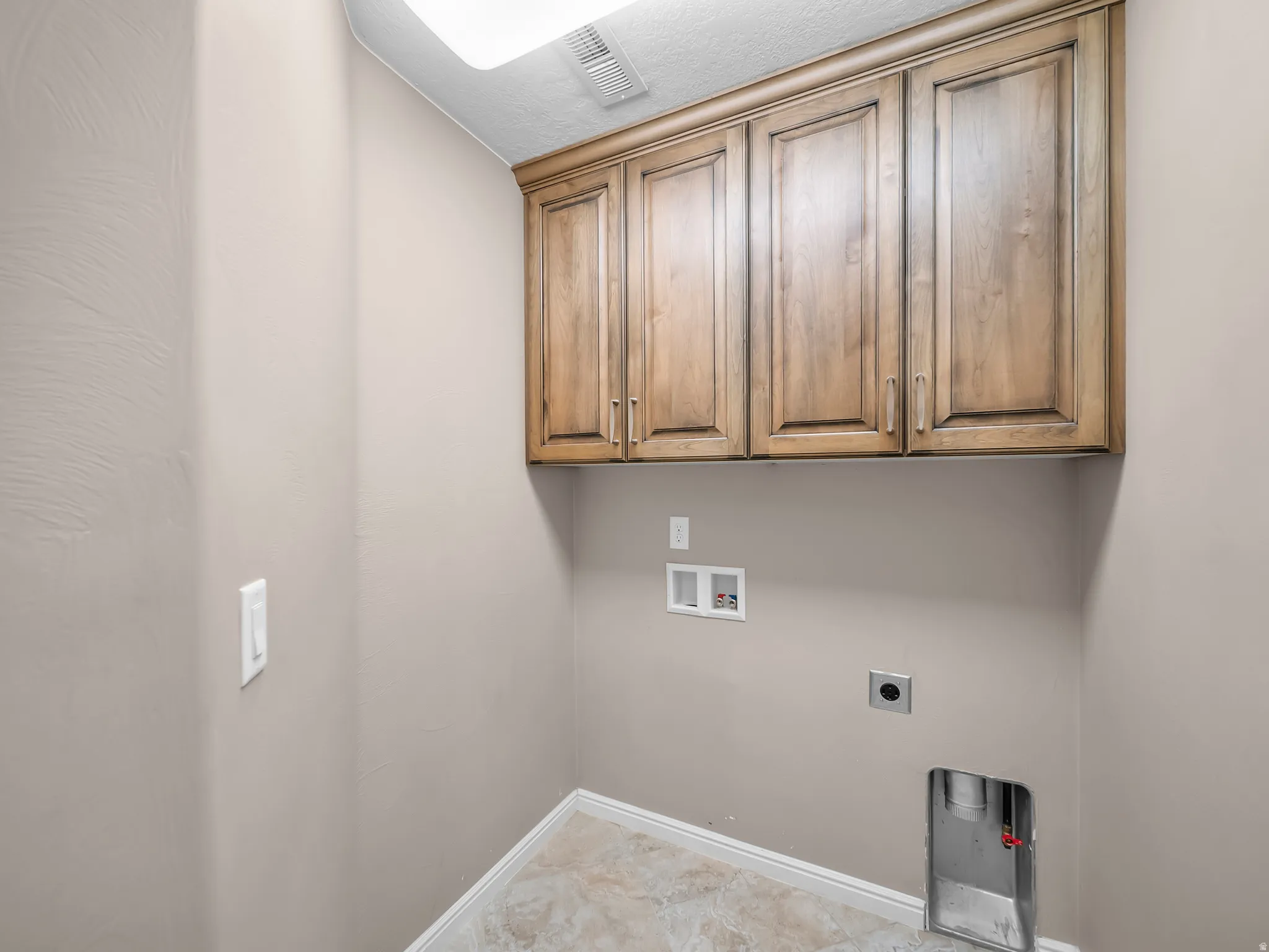 Built-in upper cabinetry with wood-finish doors, ceiling-mounted lighting fixture, and tiled flooring