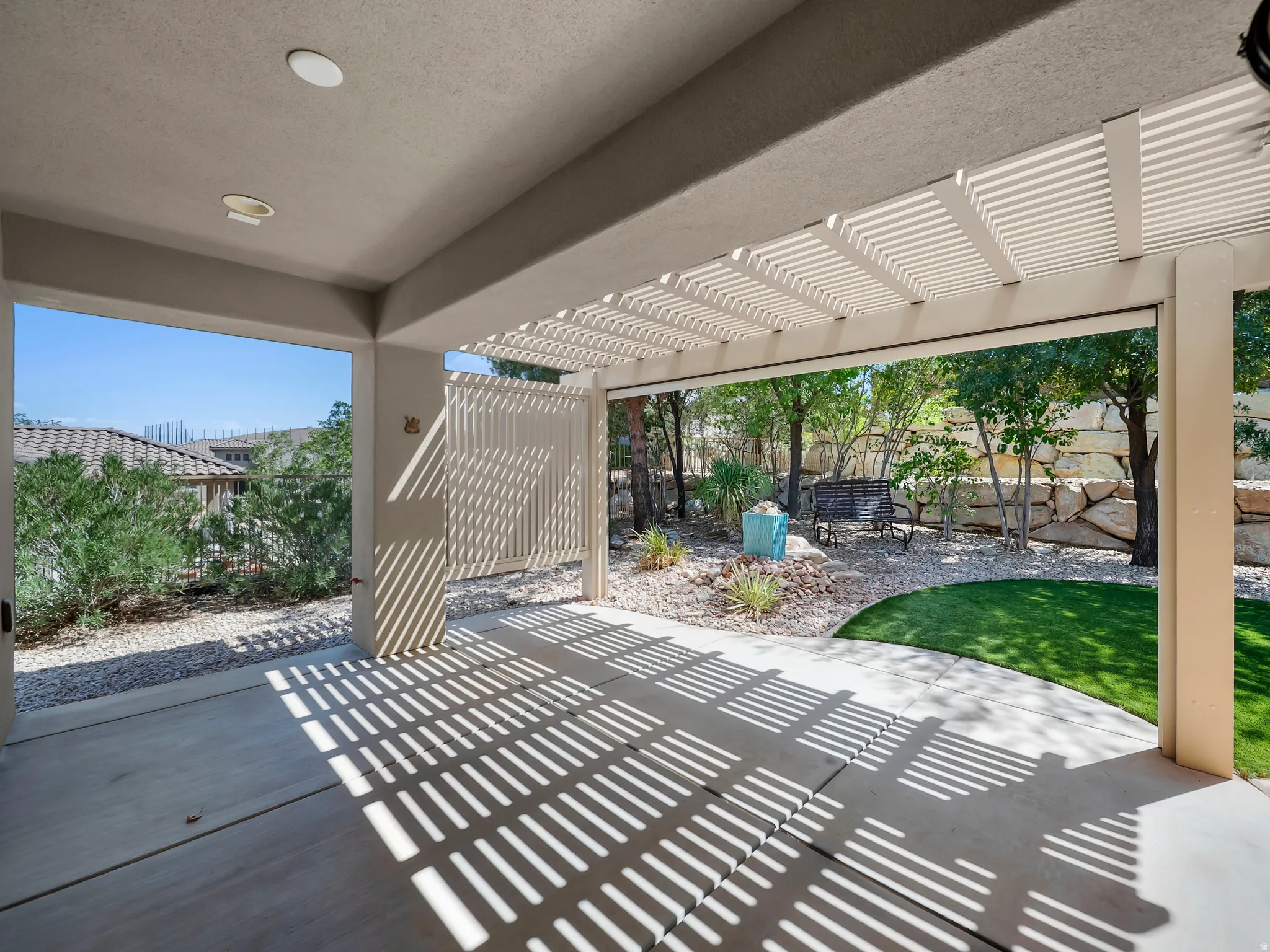 Covered patio with integrated lighting, pergola, concrete flooring, and an artificial turf area