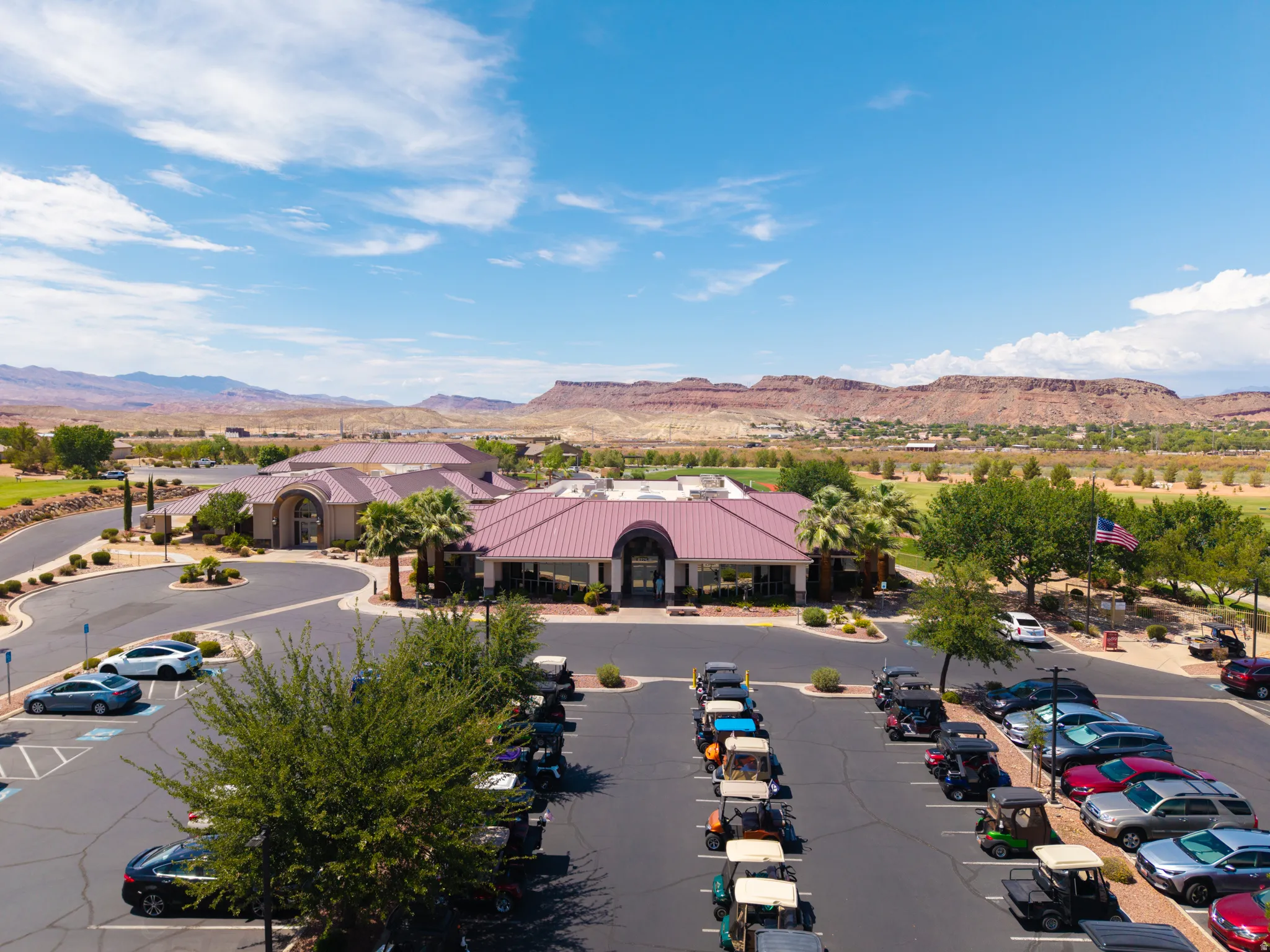 Expansive paved parking area, lush landscaping, and a distinctive main building with a red tile roof