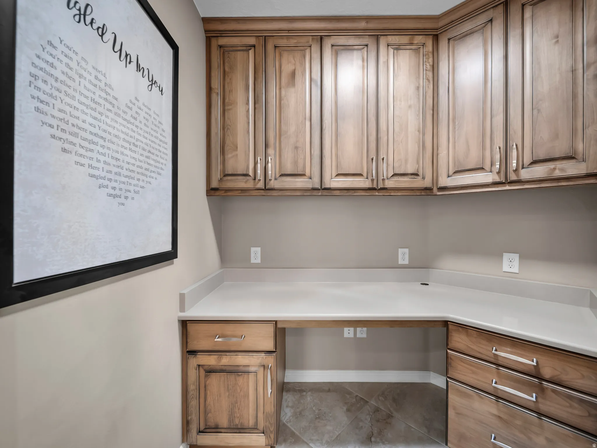 L-shaped countertop with integrated desk space, wood-finish cabinetry, and tiled flooring