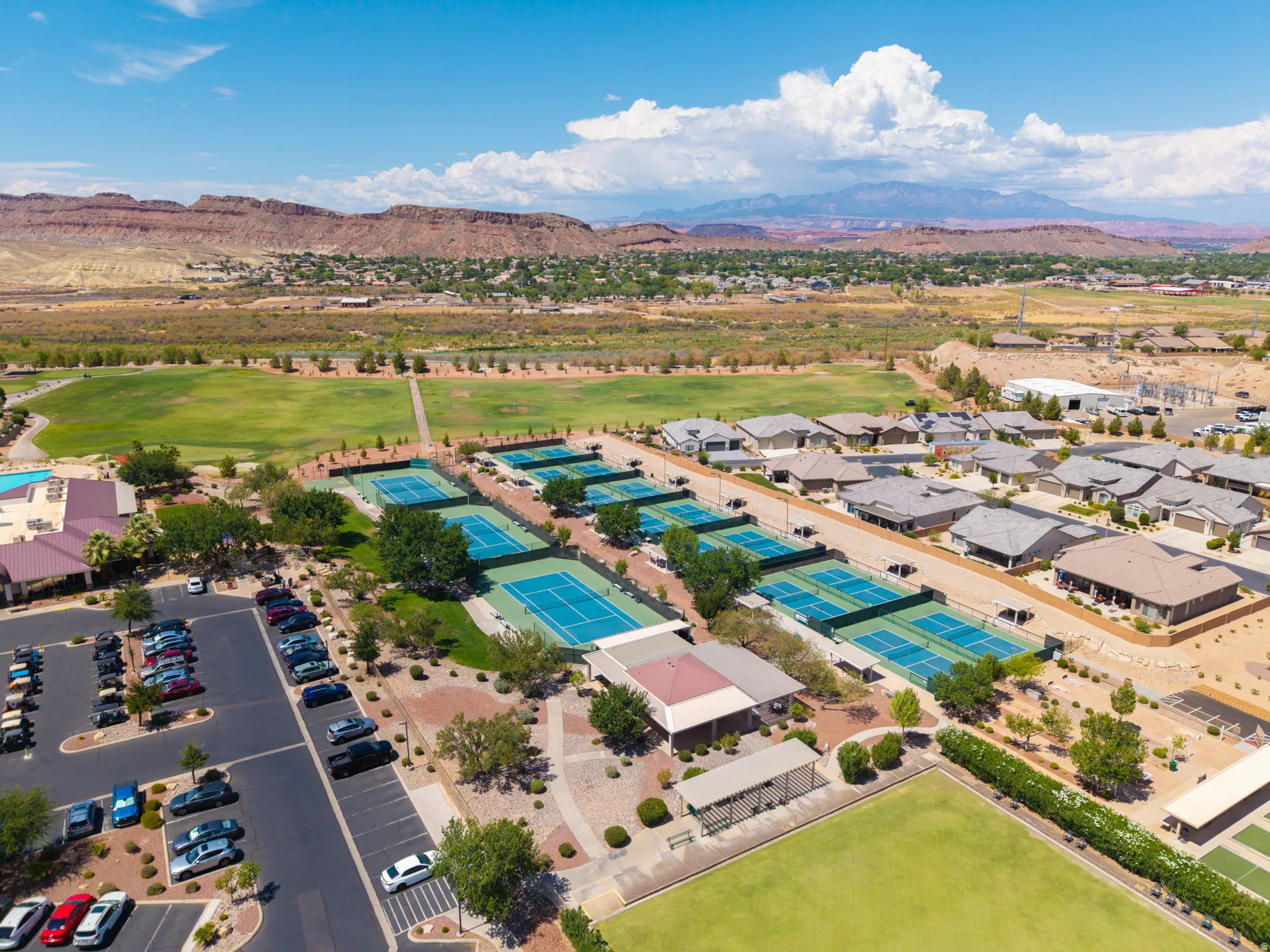 Community amenities featuring multiple tennis courts, manicured green spaces, and a large parking area