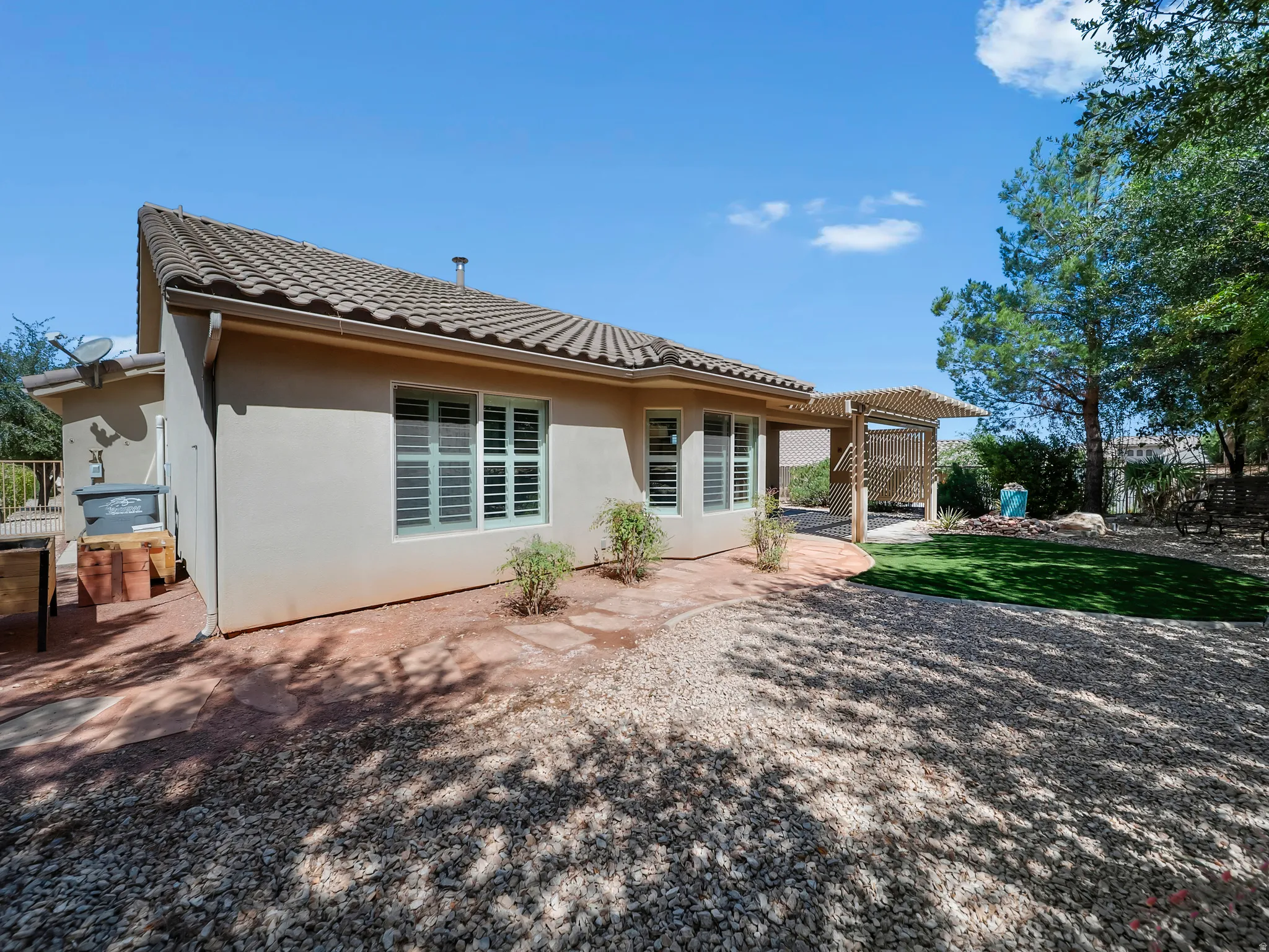 Exterior featuring a tile roof, stucco siding, and multiple windows with louvered shutters