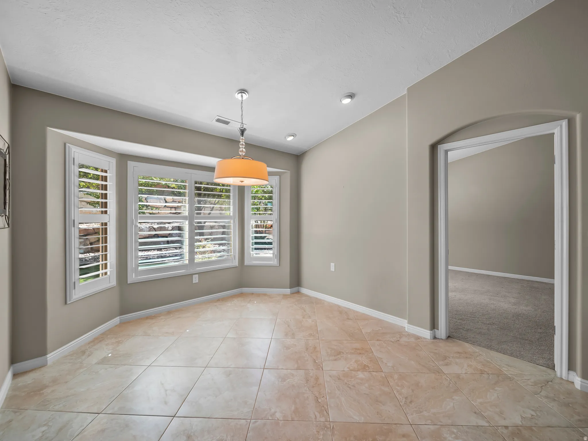 Bay window with plantation shutters, tile flooring, recessed lighting, and a drum pendant light fixture