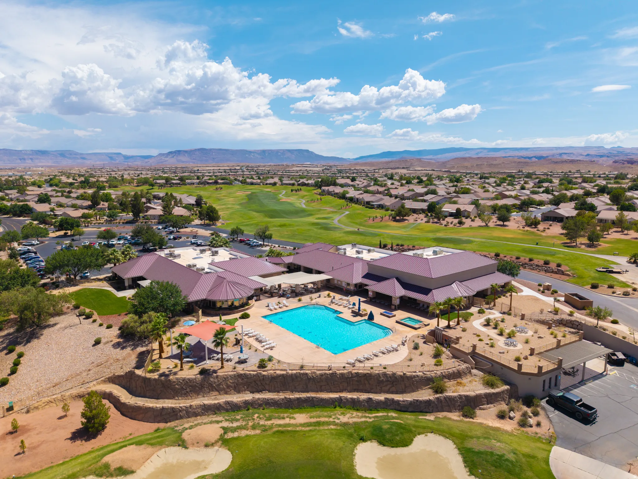 Expansive community pool with an integrated spa, surrounded by a paved deck with lounge chairs