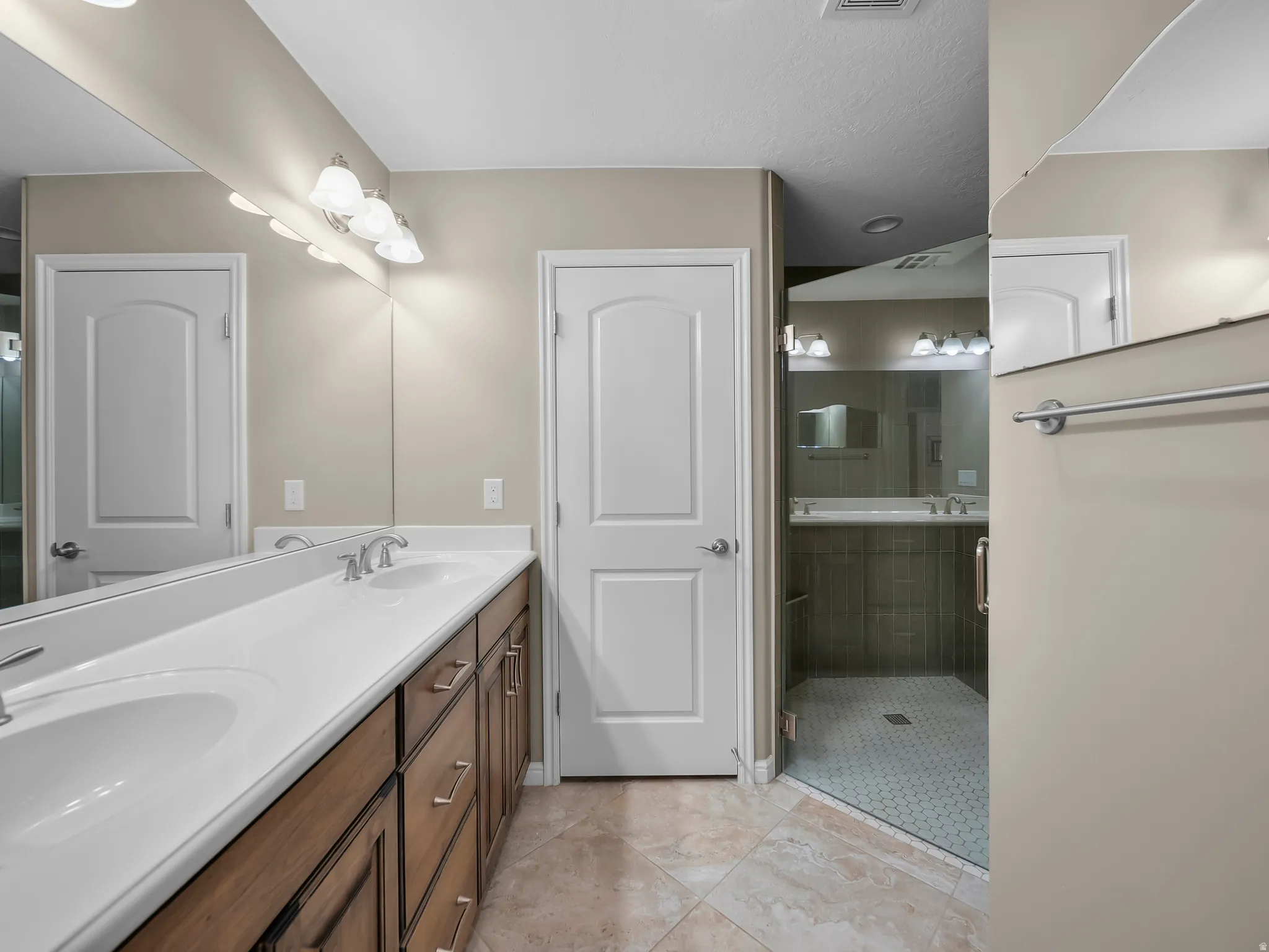 Double vanity with integrated sinks, wood-finish cabinetry, brushed nickel hardware, and tile flooring