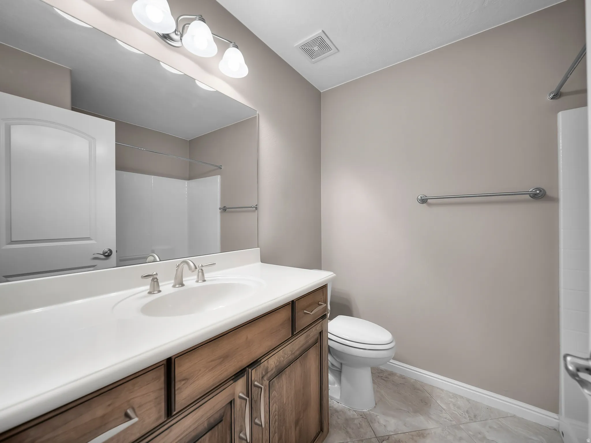 Vanity with wood-finish cabinetry, white countertop, and an undermount sink