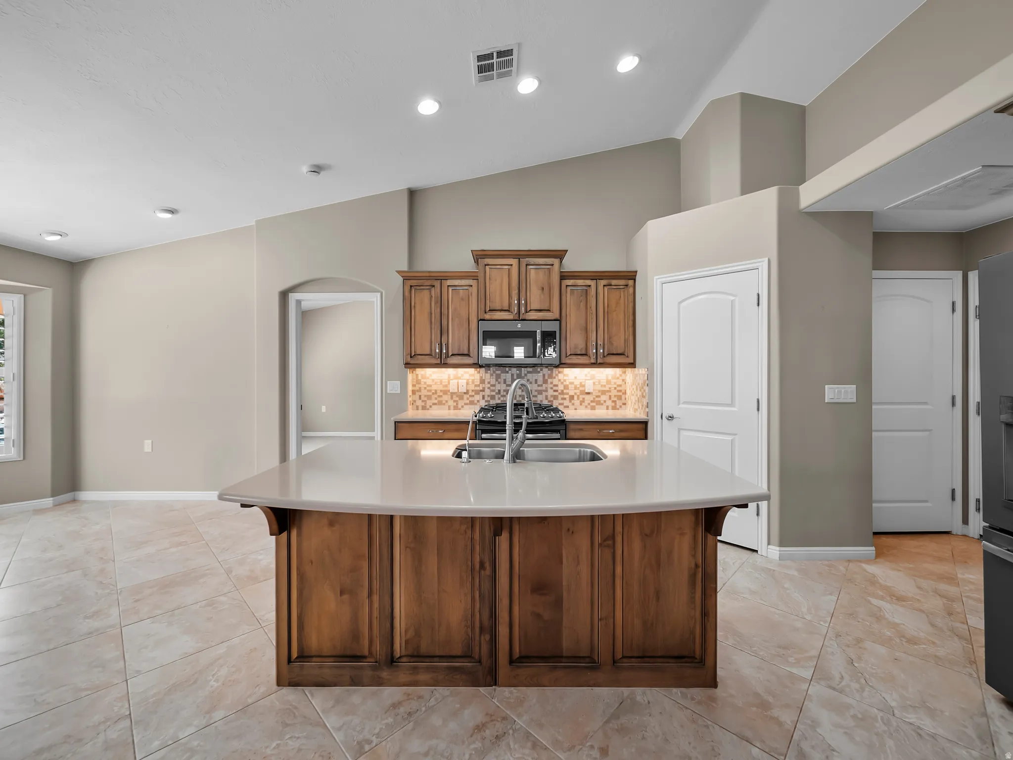Kitchen island with wood-finish cabinetry, light-toned countertop, and integrated sink