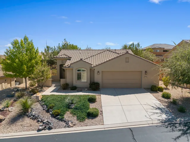 Stucco exterior with a tiled roof, an integrated two-car garage, a concrete driveway, and drought-tolerant landscaping