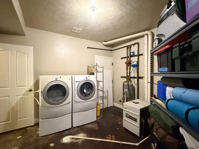 Utility room featuring a washer and dryer, built-in shelving, and exposed piping