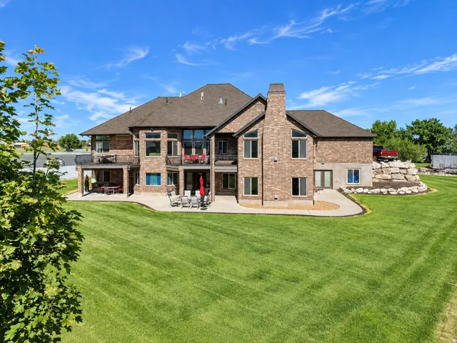 Brick exterior with multiple windows, covered patio, open-air patio, and a stone retaining wall