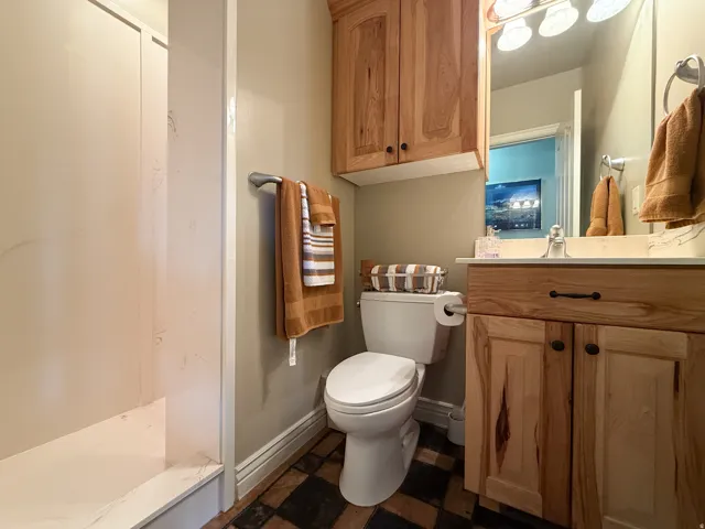 Wood-finish vanity with a single basin sink, wall-mounted mirror, and overhead lighting