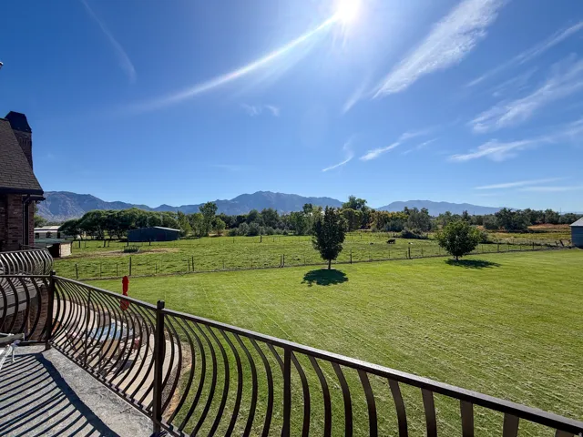 Balcony with wrought iron railing, expansive green lawn, and distant mountains