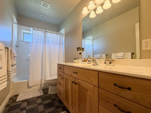 Wood-finish vanity with multiple storage drawers, white countertop, and a large wall-mounted mirror