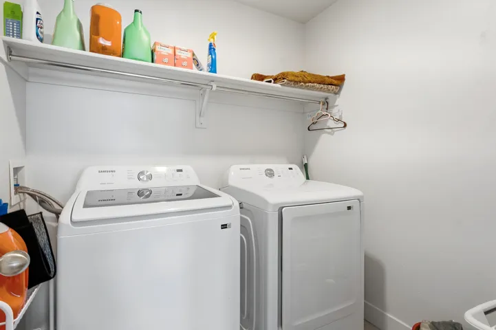 Dedicated laundry area featuring white appliances, a built-in shelf, and an integrated hanging rod