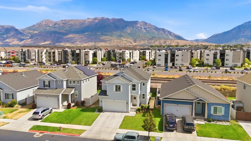 Residential neighborhood featuring single-family homes and multi-story buildings, with mountain scenery in the background