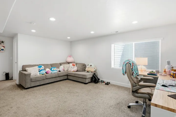 Recessed lighting, light-toned carpeting, and a large window with blinds