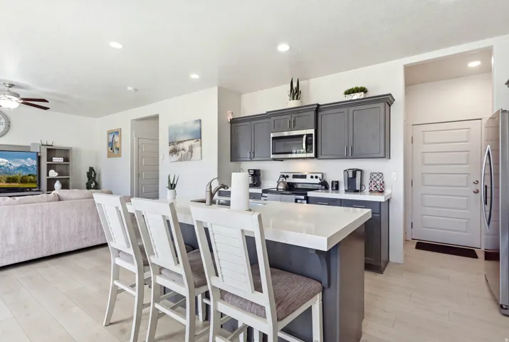 Kitchen featuring gray cabinetry, stainless steel appliances, and an island with a light-toned countertop