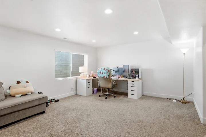 Recessed lighting, light-toned carpeting, a window with blinds, and white painted walls