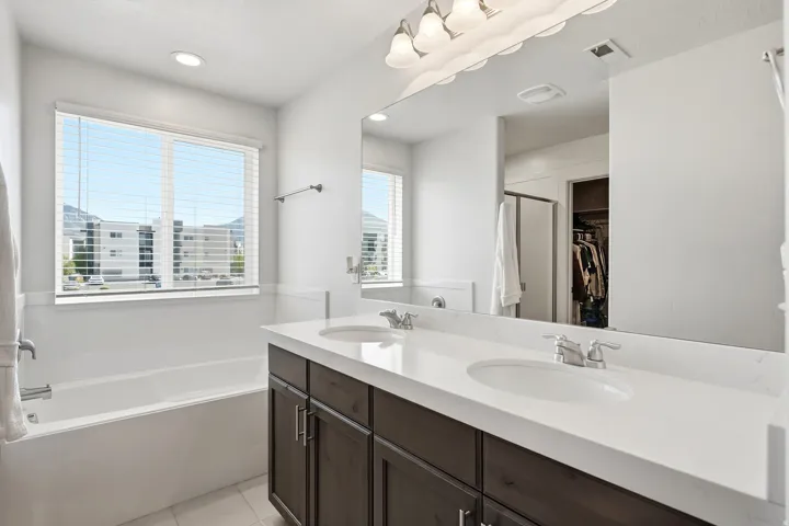 Dual vanity with white countertop, chrome fixtures, and dark wood-finish cabinetry
