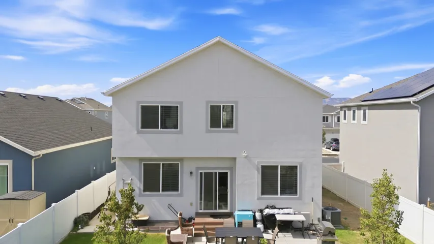 White stucco exterior, multiple windows, sliding glass door, wood deck, fenced yard